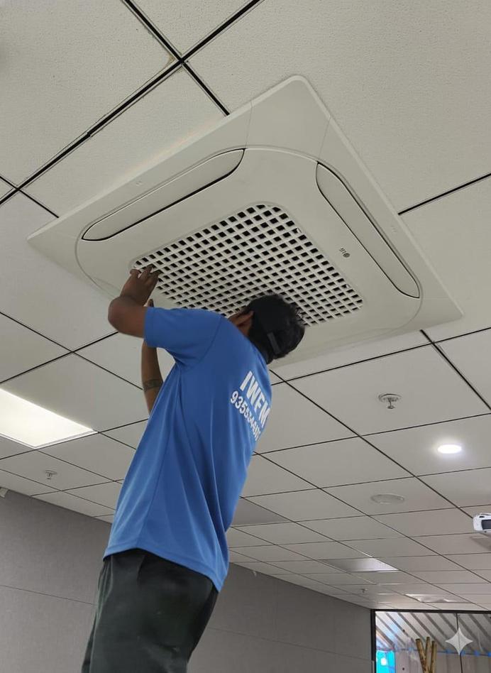 IWFM technician servicing a ceiling AC vent